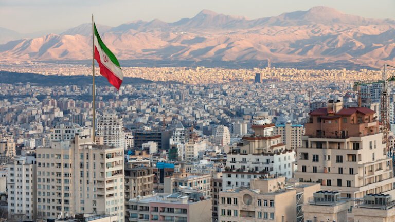 Waving,Iran,Flag,Above,Skyline,Of,Tehran,At,Sunset.