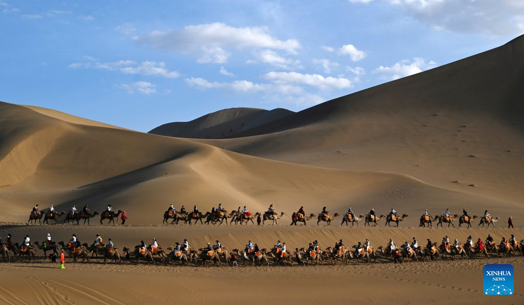 Tourists ride camels at the Mingsha Mountain and Crescent Spring Scenic Area in Dunhuang, northwest China's Gansu Province, June 19, 2026. People enjoyed the three-day holiday of the Dragon Boat Festival, also called Duanwu Festival, which falls on June 19 this year, via various activities across the country. (Photo by Zhang Xiaoliang/Xinhua)