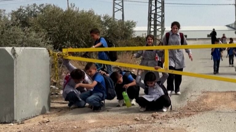 Palestinian children crawl under Israeli military gates to get to school